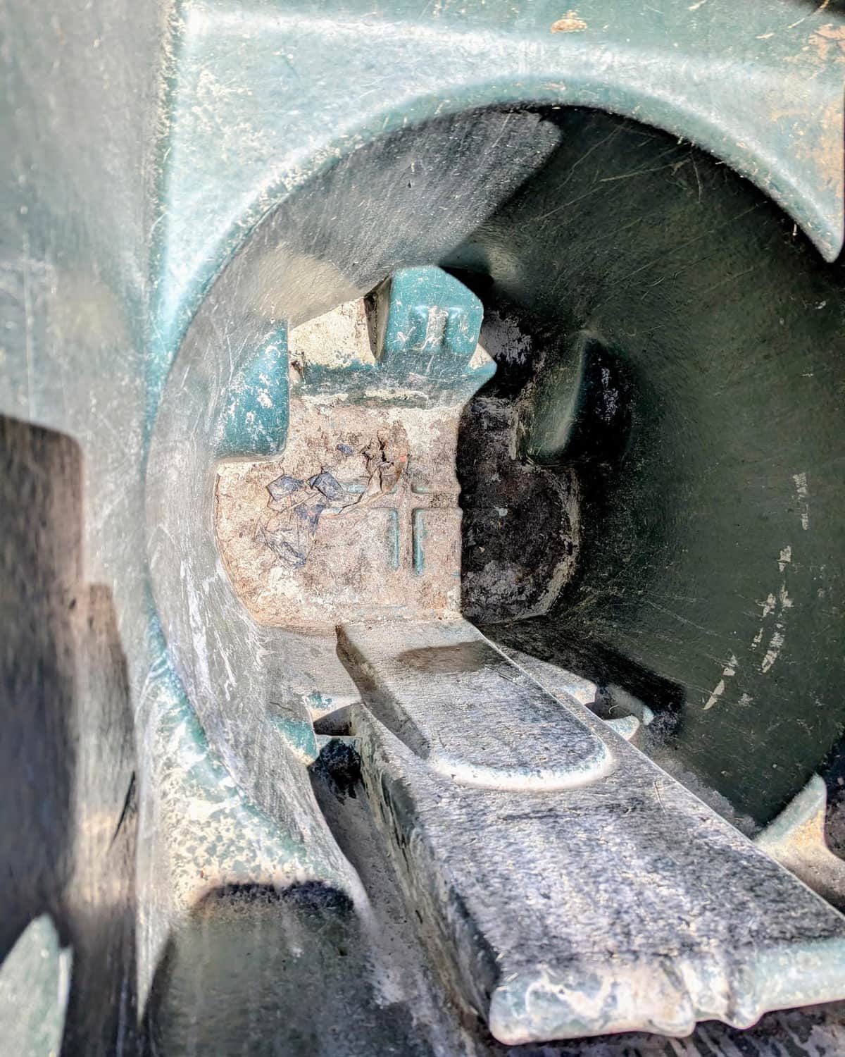 Inside a residential trash can before cleaning, with caked-on grime and black buildup covering the base and hinge